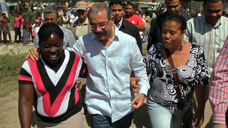 Presidente Danilo Medina camina junto a dos mujeres